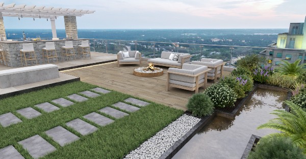 Rooftop patio with stone pavers, modern outdoor seating around a fire pit, a pergola bar area, and landscaped greenery overlooking a city skyline.