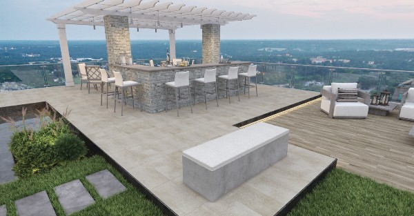 Rooftop patio with stone tile flooring, a pergola-covered outdoor bar, and lounge seating overlooking a scenic landscape.