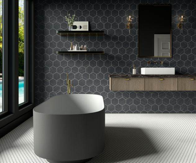 Modern bathroom with dark hexagonal tiles, floating wooden vanity, grey bathtub, and large windows.