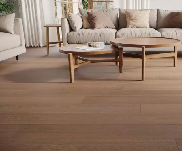 A living room featuring a sofa, wooden coffee tables, and hardwood flooring.