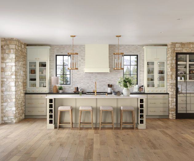 Modern farmhouse kitchen with central island, wooden stools, pendant lighting, and stone wall accents.