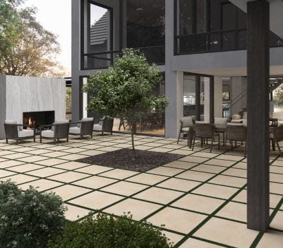 Modern outdoor patio with grid-patterned tile flooring, a central tree planting bed, seating area, and fireplace.