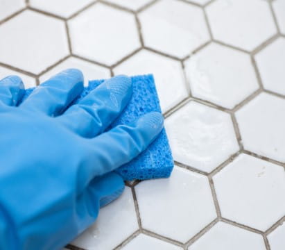 Cleaning octagonal white tile in a bathroom