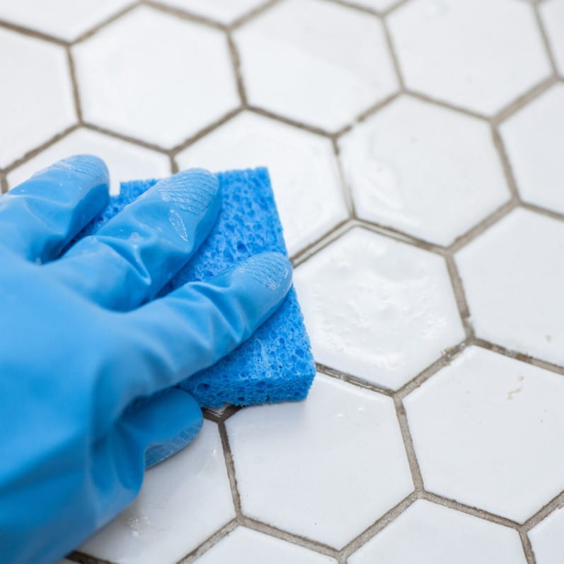 Cleaning octagonal white tile in a bathroom