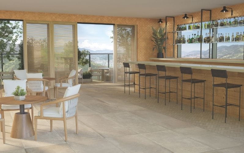 A bar area with high stools and chairs, bright lighting, and large windows showing an outdoor view.