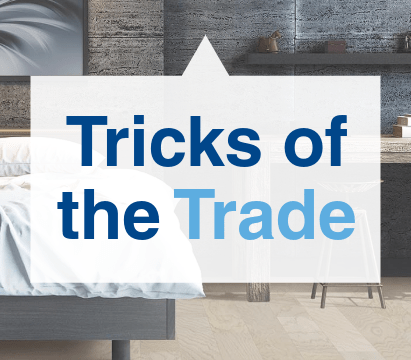Text reading 'Tricks of the Trade' on a modern bedroom background with gray and wooden decor elements.