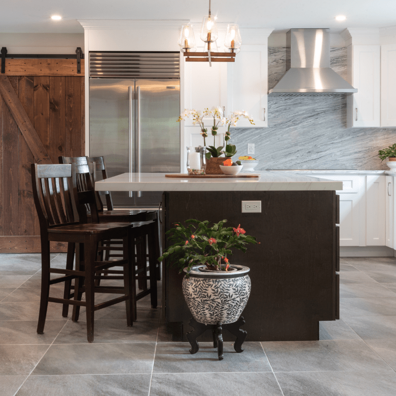 A bold kitchen island with light gray countertops anchors the open layout, complemented by stainless steel appliances and a matching backsplash. Natural wood tones add warmth to the contemporary design.