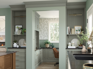 A modern kitchen showcasing green Decora cabinets, a workspace nook, and light wood flooring.
