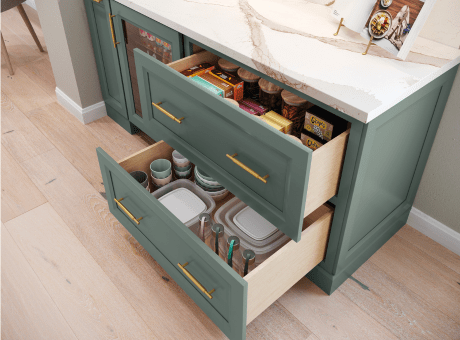Green kitchen drawers with golden handles storing utensils and containers, under a marble countertop.