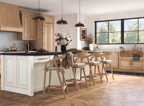 A modern kitchen featuring wooden cabinets, a central island with chairs, pendant lighting, and a bright windowed view.