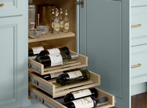 A kitchen cabinet with pull-out shelves storing wine bottles and beverage accessories.