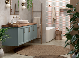A modern bathroom with a wooden floating vanity, pastel green cabinets, a round rug, ladder-style towel rack, and plants adding a natural touch.