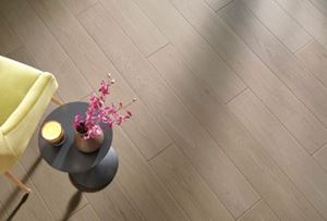COREtec flooring in a close-up view, highlighted with a table holding pink flowers, a candle, and a yellow chair.