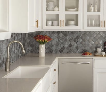 Close-up of Daltile Vintage Metals tile in Iron Arabesque pattern, showcasing a dark, metallic finish with intricate curved shapes and a textured, antique-inspired surface.