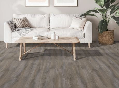 A modern living room featuring Harding laminate flooring, a white sofa, wooden coffee table, and potted plant.