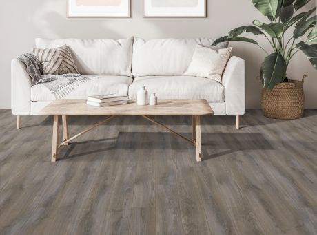 A modern living room featuring Harding laminate flooring, a white sofa, wooden coffee table, and potted plant.