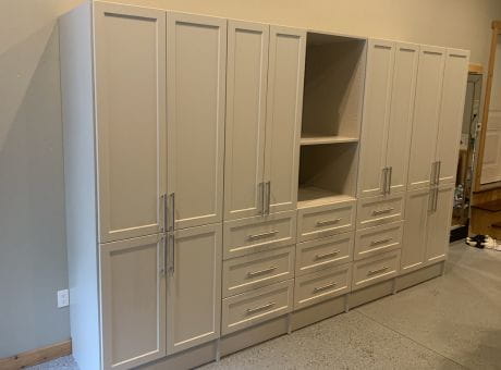 A modern storage cabinet system with multiple drawers, shelves, and cupboards in a beige finish and metal handles.