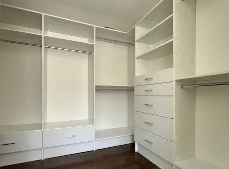 A white closet interior with shelves, drawers, and rods for clothing organization.