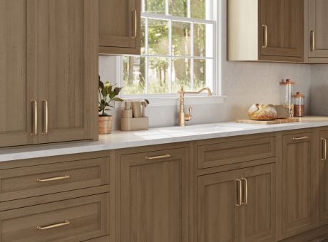 A modern kitchen with wooden cabinets and a white countertop, featuring a window in the background.