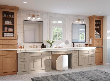 Bright bathroom with a double vanity, two framed mirrors, warm wood cabinets, and a central makeup station under a window.