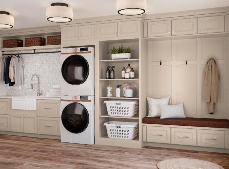 Beige built-in laundry and mudroom with stacked washer and dryer, open shelves, sink, and bench with coat hooks.
