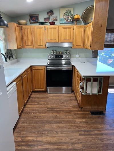 Kitchen with white countertops, light hung cabinets, and medium-stained lower cabinetry