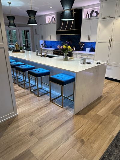White kitchen island with white cabinets and wood floors