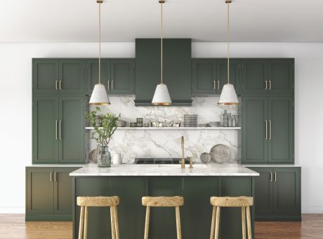 A modern kitchen with green cabinets, marble backsplash, light wood bar stools, and pendant lights.