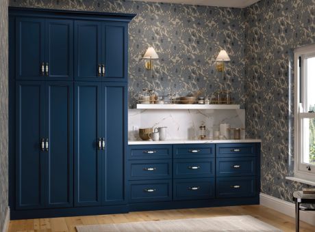 Kitchen with blue cabinets, floral wallpaper, and wooden floor.