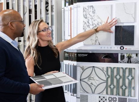 Individuals examining tile samples displayed on panels in a showroom.