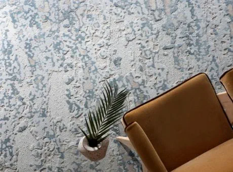A textured blue-and-white carpet with a modern chair and a potted plant.