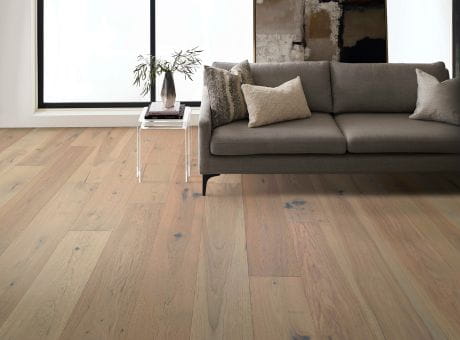 Living room with Anderson Tuftex Imperial Pecan hardwood flooring, modern sofa, glass side table, and large window.