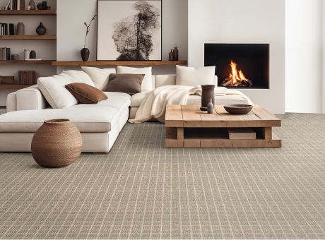 Contemporary living room with white sectional sofa, beige textured carpet, wooden coffee table, and fireplace.