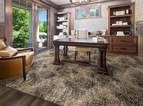 Home office with wooden furniture, a leather chair, bookshelves, and a patterned carpet.