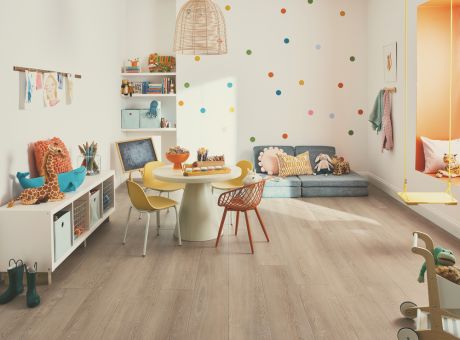 A bright and organized children's playroom featuring wooden flooring, colorful furniture, and playful decor.