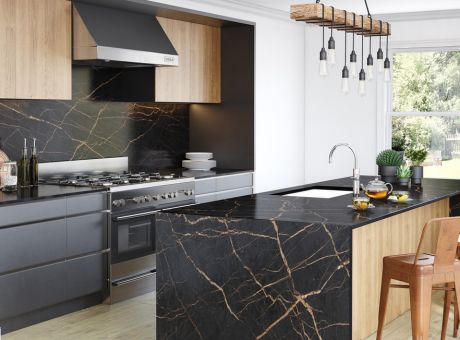 Modern kitchen with black and gold veined countertops, wooden cabinets, and pendant lighting.
