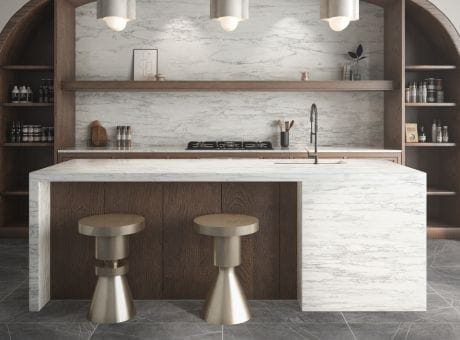 Modern kitchen with marble countertops, wooden cabinetry, stylish stools, and built-in shelves.