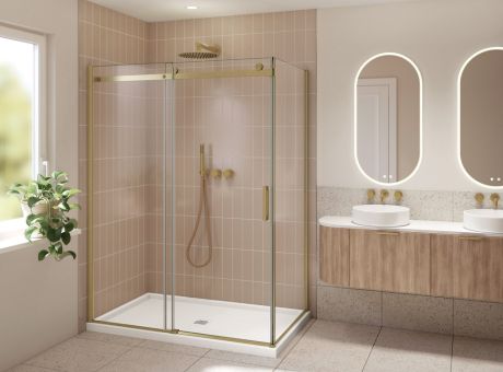 Modern bathroom with a gold-accented shower enclosure, beige tile walls, double vanity with circular mirrors, and a potted plant.