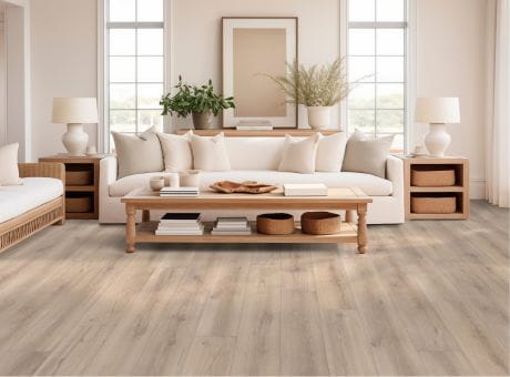 Living room with hardwood flooring, featuring a white sofa, wooden furniture, and decorative plants.