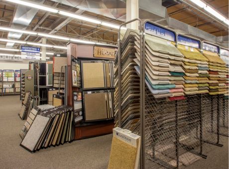 Interior of a carpet store with a variety of carpets arranged on racks, showcasing colors and textures.