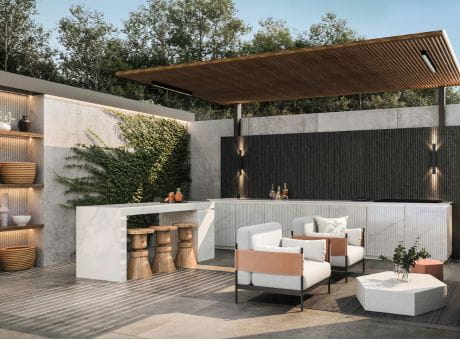 An outdoor patio with a bar counter, modern chairs and tables, decorative plants, and a wooden canopy.