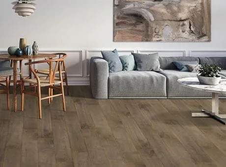 Living room with gray sofa, hardwood flooring, a white coffee table, wooden dining furniture, and wall decor.