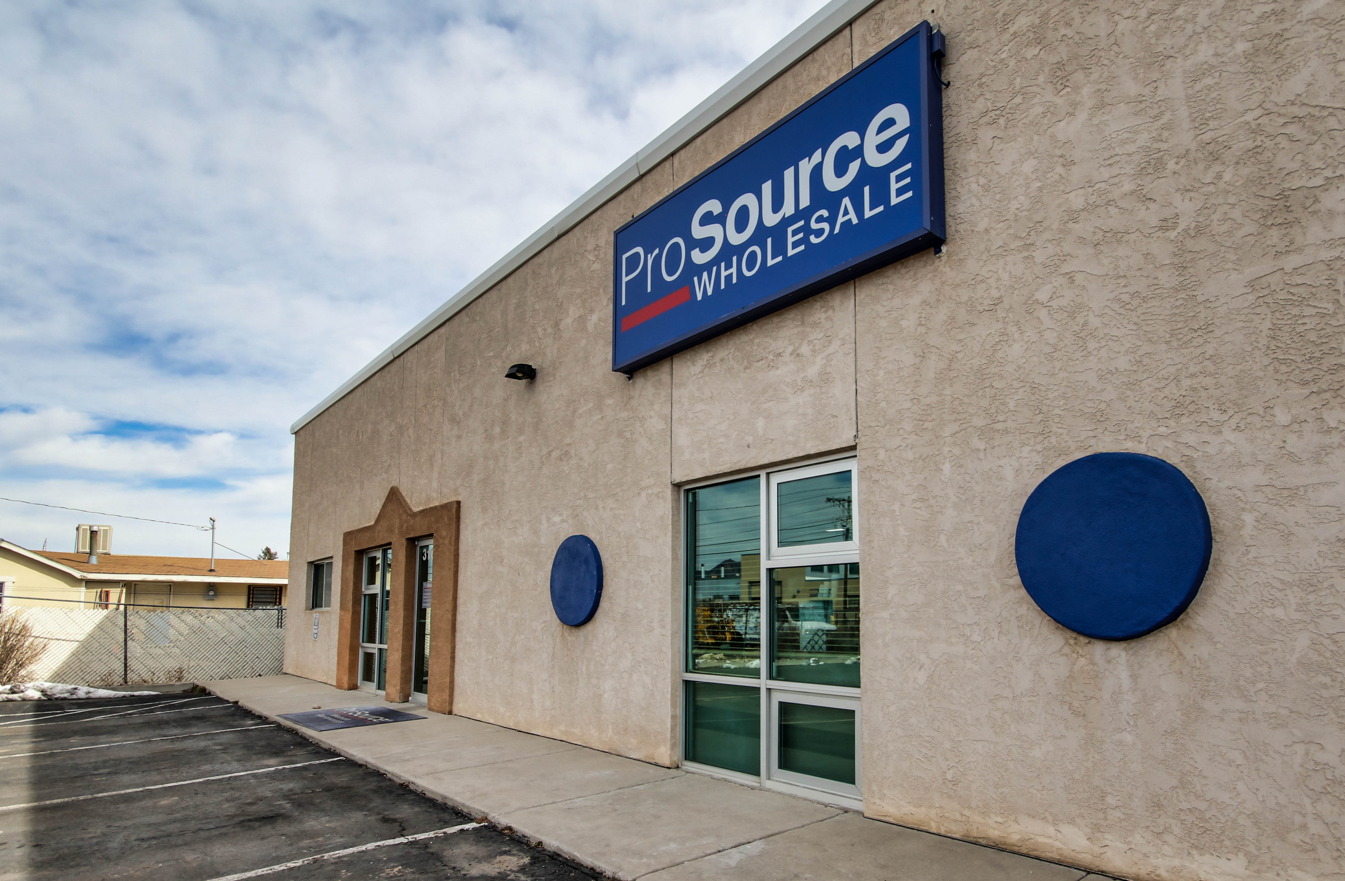 Exterior of a ProSource Wholesale building with parking lot and signage in Colorado Springs.