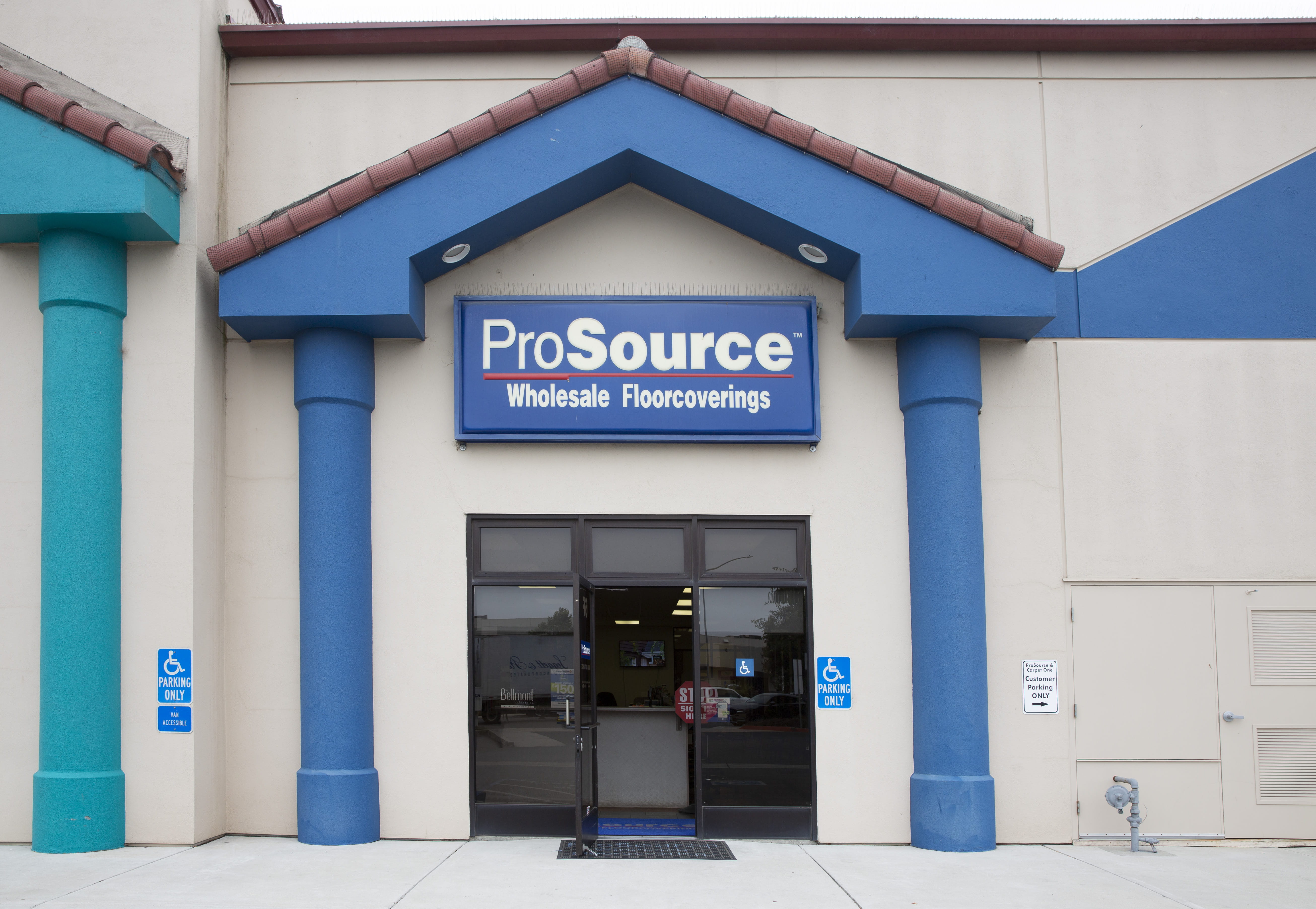 The exterior of a ProSource Wholesale Floorcoverings store with blue accents and accessibility signage.