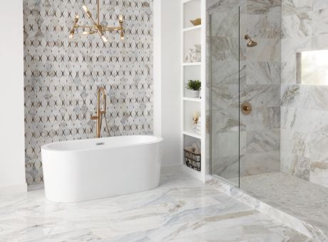 Modern bathroom with marble tiles, a standalone tub, glass shower enclosure, patterned wall, and white shelving unit.