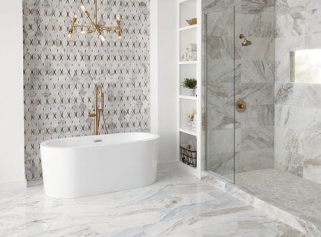 Modern bathroom with marble tiles, a standalone tub, glass shower enclosure, patterned wall, and white shelving unit.