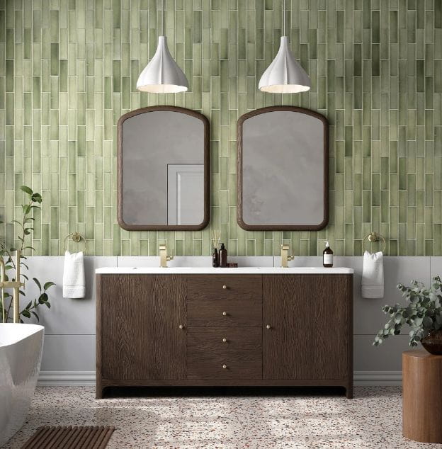 Modern bathroom interior with a brown wooden vanity, green tiled wall, mirrors, and hanging lights.