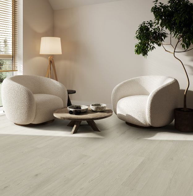 A stylish living room with two white armchairs, a round coffee table, and a potted plant on light-toned flooring.
