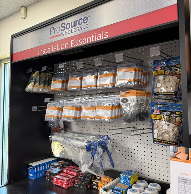 Shelf display of installation essentials including adhesives, tools, and sanding products at ProSource Wholesale store.