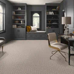 A modern home office with built-in shelving, desk, chair, and window seating area.